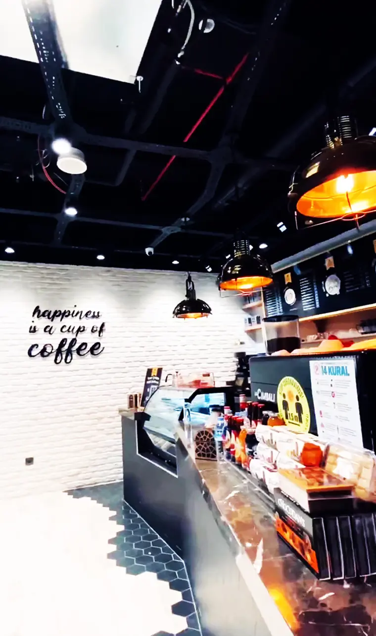 Counter and brick wall with pendant lamps and “happiness is a cup of coffee” lettering
