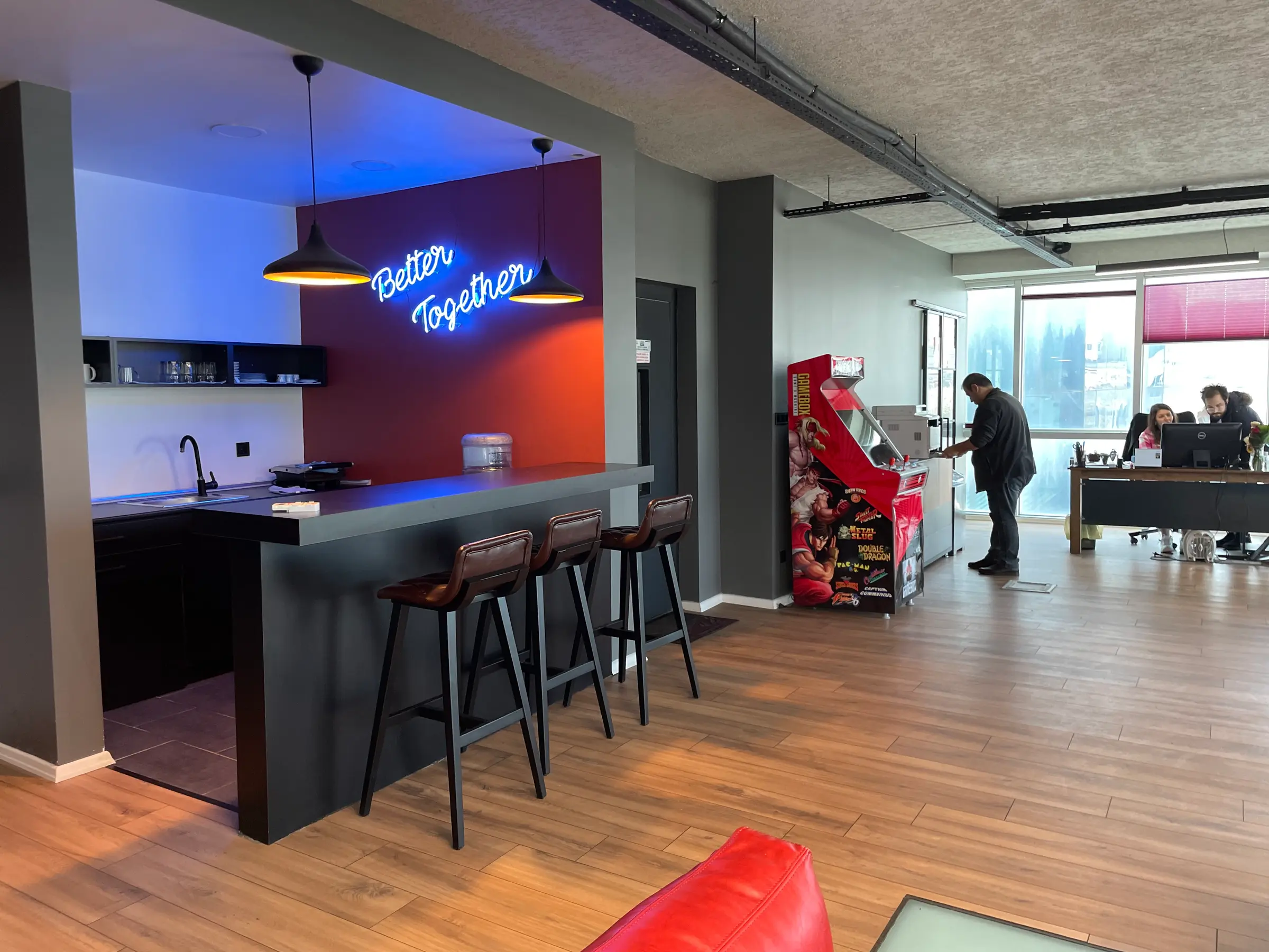 Blue-lit kitchen niche with bar stools and an arcade machine