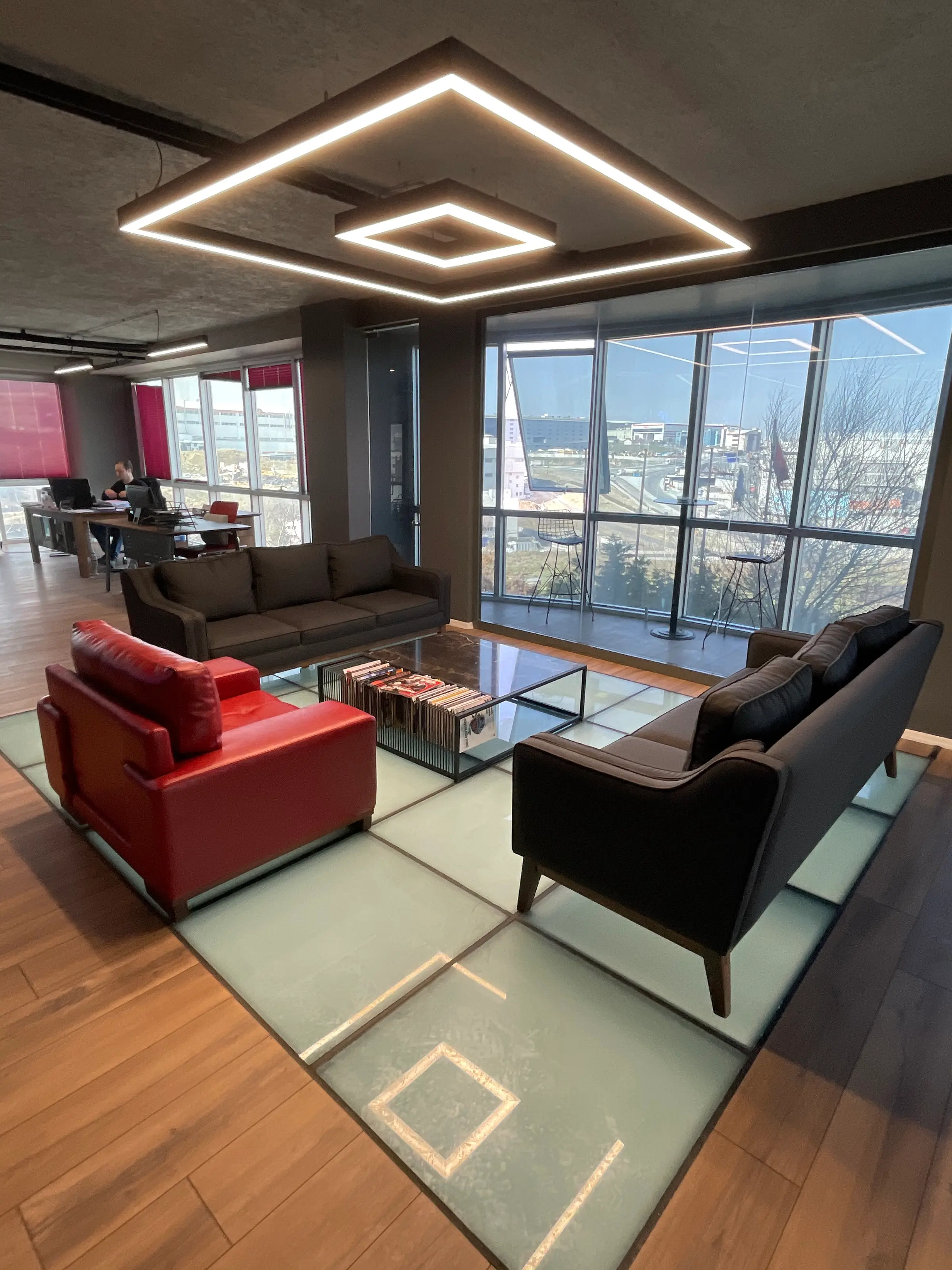 Vertical view: square LED fixture, glass floor and red armchair