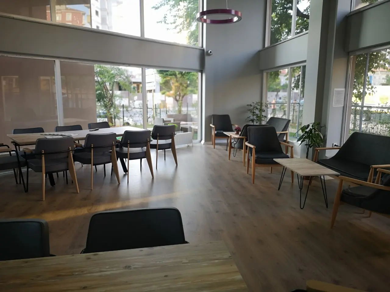 High-ceilinged dining and sitting hall with table groups and large windows.