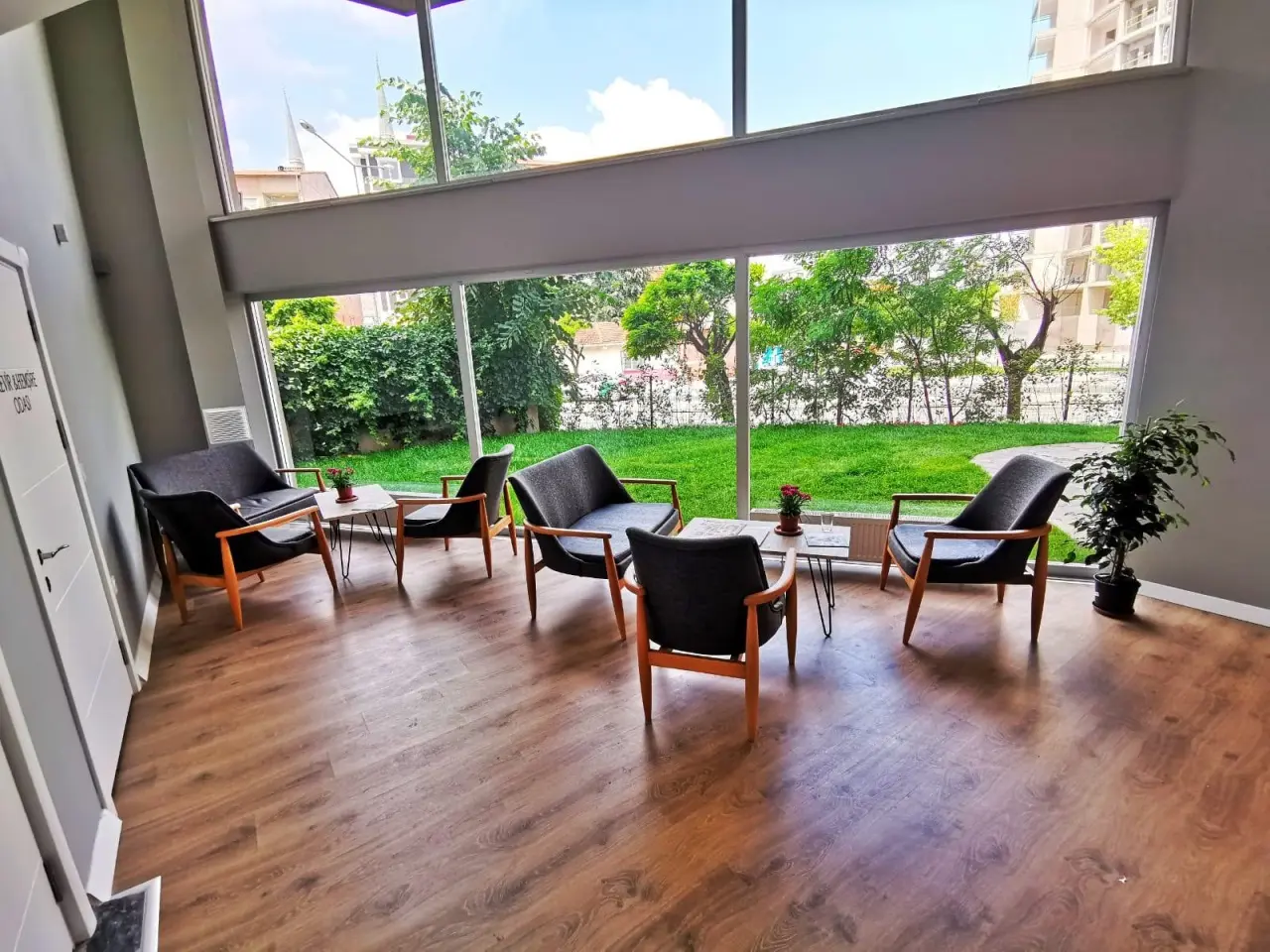 Social lounge with large windows onto the garden, armchairs and a timber floor.
