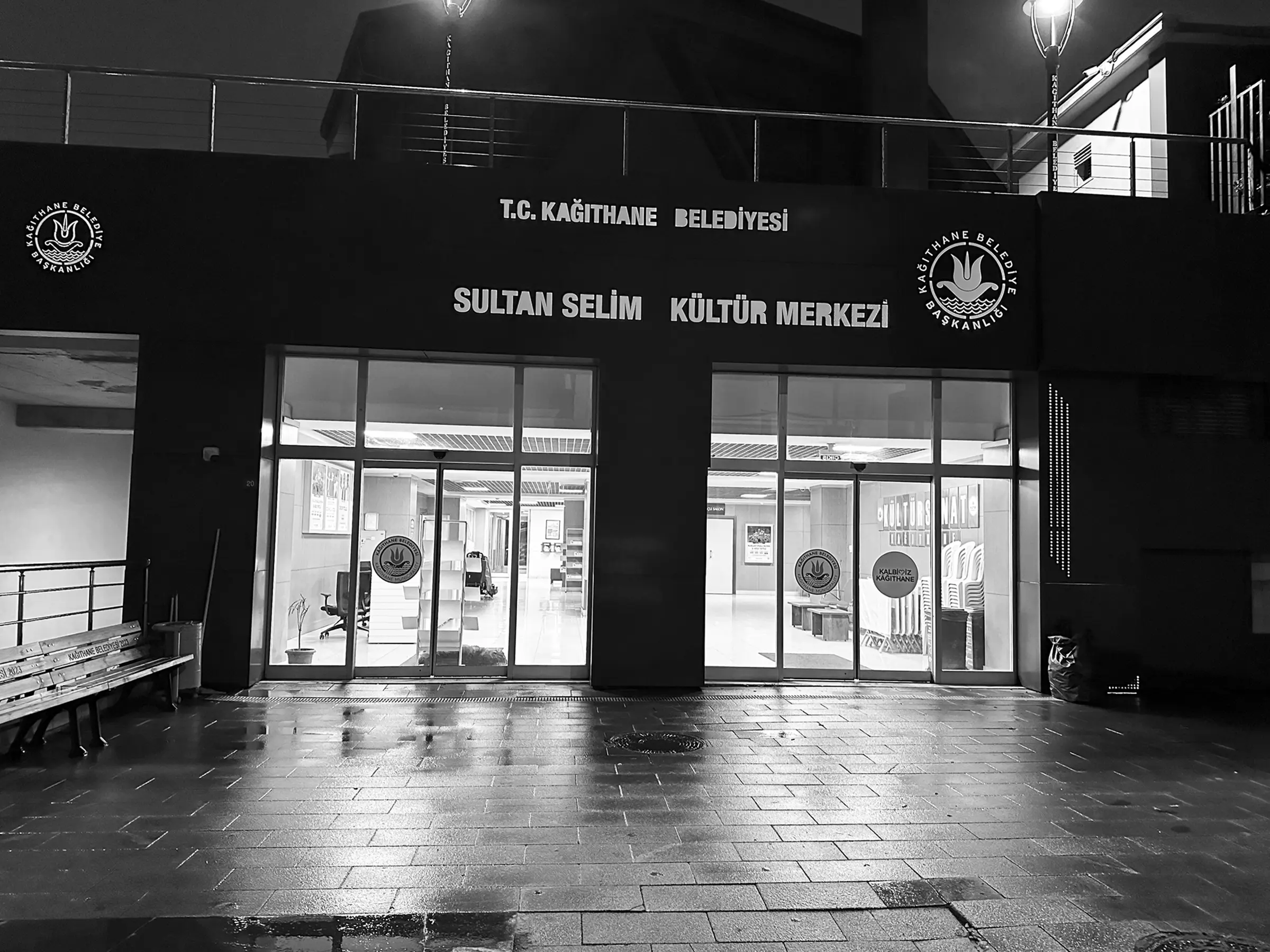 Entrance of the cultural centre at night, rain-soaked paving